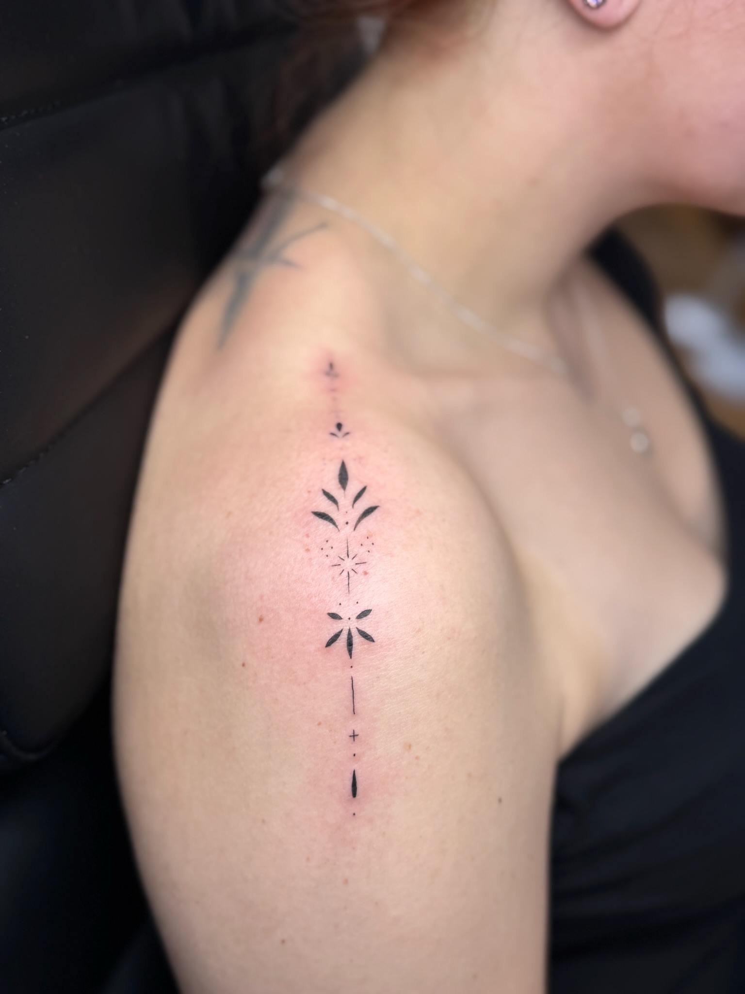 A delicate ornamental fine line piece on the shoulder